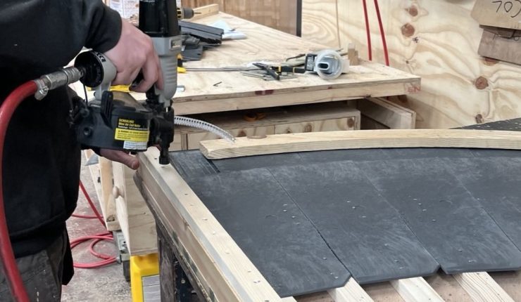 Man using a nail gun to manufacture sheds, fencing, and garden buildings.
