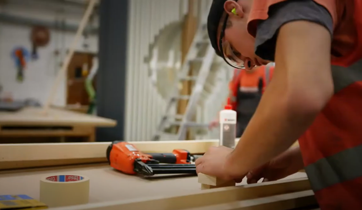 Man using a brad nailer in an exhibition manufacturers workshop to fix two pieces of timber together.